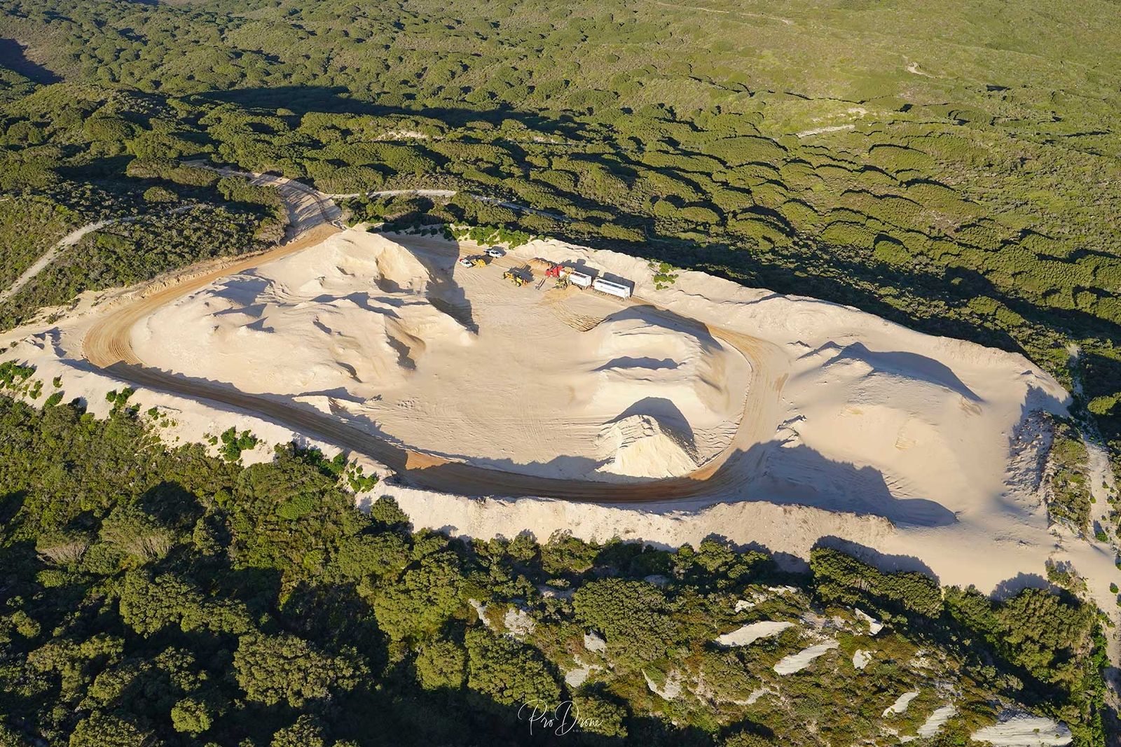 Aerial view of the Great Southern Lime pit at Nullaki, a pale limestone pit with trucks, surrounded by coastal bush